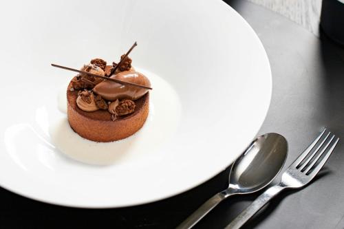a chocolate dessert on a white plate with a fork and knife at Hotel Luc, Autograph Collection in Berlin