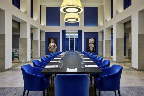 a long table in a room with blue chairs at Hotel Luc, Autograph Collection in Berlin