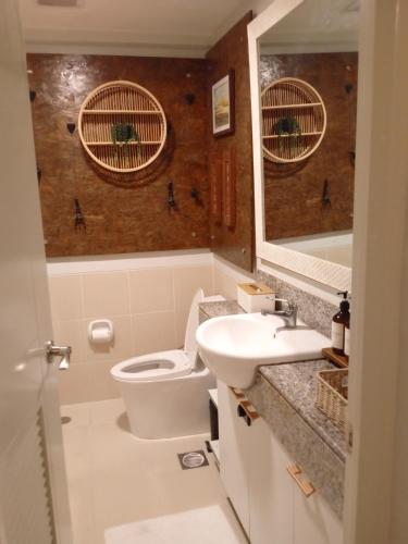 a bathroom with a toilet and a sink and a mirror at Cozy 2BR Condominium Unit- Verdon Parc in Davao City