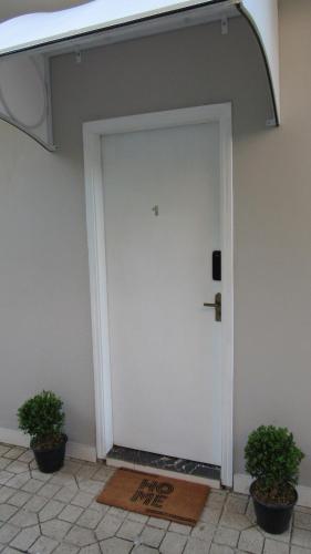 a white door with two potted plants next to it at Casa1sn - Casa completa com jardim privativo e chuveirão refrescante! in Serra Negra
