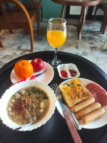 a black plate with food and a glass of orange juice at อยู่สบายวิลล่า ยโสธร in Yasothon