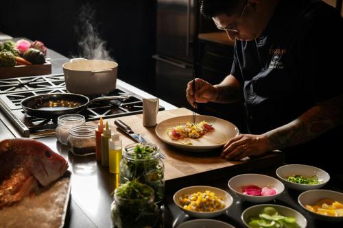 a man preparing a plate of food in a kitchen at Epicurean Atlanta, Autograph Collection in Atlanta