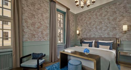 a bedroom with a bed with a desk and a chair at Hotel Taschenbergpalais Kempinski in Dresden