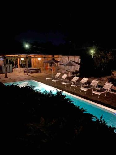 a pool with lounge chairs and umbrellas at night at Condominio Fundo Zapallar in Cachagua