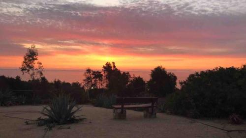 a bench in a park with a sunset in the background at Condominio Fundo Zapallar in Cachagua