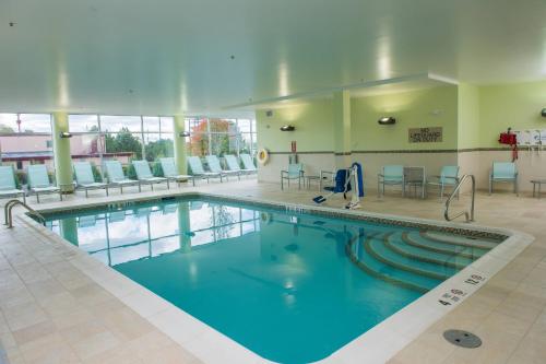 a large pool in a hotel lobby with chairs and tables at SpringHill Suites by Marriott Buffalo Airport in Williamsville