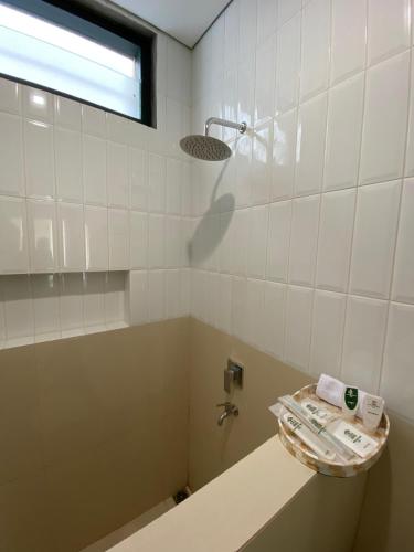 a white tiled bathroom with a sink and a shower at Agung Guest House by RF in Timuran