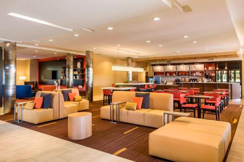 a hotel lobby with chairs and tables and a bar at Courtyard by Marriott Kalamazoo Portage in Portage