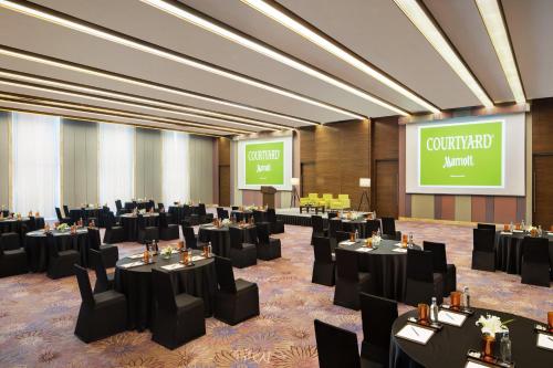 a conference room with black tables and chairs and a screen at Courtyard by Marriott Bengaluru Outer Ring Road in Bengaluru