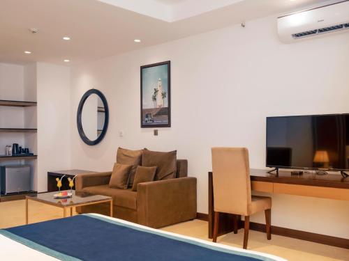 a living room with a couch and a desk with a television at Negombo Ocean Breeze Apartments in Negombo