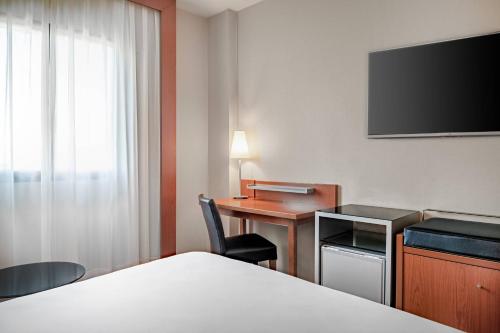 a hotel room with a bed and a desk and a television at AC Hotel Badajoz by Marriott in Badajoz