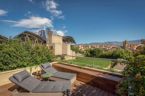 a patio with two chairs and a table on a deck at Hotel Marqués de Riscal, a Luxury Collection Hotel, Elciego in Elciego