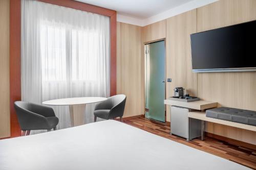 a hotel room with a bed and a flat screen tv at AC Hotel Badajoz by Marriott in Badajoz