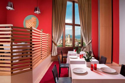 a restaurant with white tables and chairs and red walls at Hotel Marqués de Riscal, a Luxury Collection Hotel, Elciego in Elciego