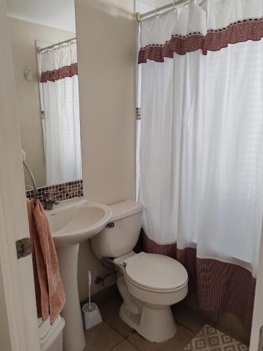 a white bathroom with a toilet and a sink at La Serena casa Puertas del Mar cerca del Faro in La Serena