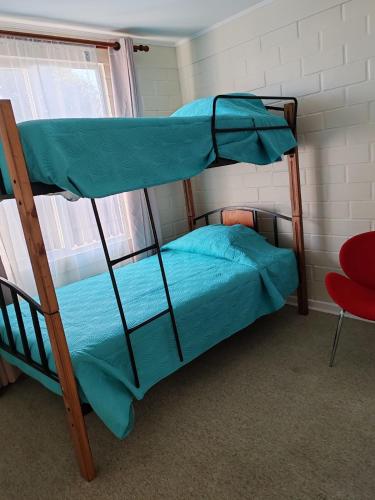 two bunk beds in a room with a red chair at La Serena casa Puertas del Mar cerca del Faro in La Serena