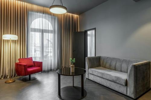 a living room with a couch and a red chair at The Marmorosch Bucharest, Autograph Collection in Bucharest