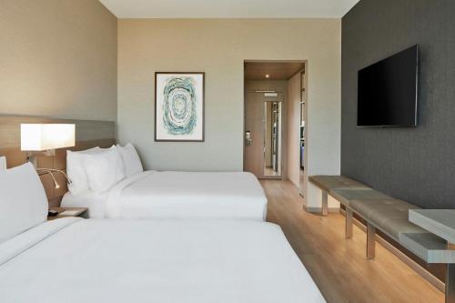 a hotel room with two beds and a flat screen tv at AC Hotel by Marriott Austin Hill Country in Austin