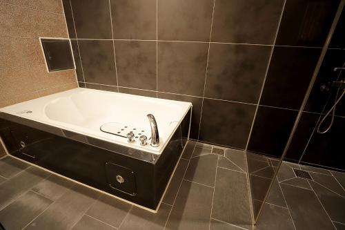a bath tub with a sink in a tiled bathroom at Gyeongju Liebe Stay in Gyeongju