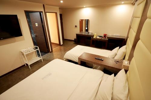a hotel room with two beds and a television at Gyeongju Liebe Stay in Gyeongju