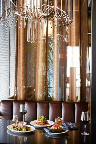 two plates of food on a table with wine glasses at The Otis Hotel Austin, Autograph Collection in Austin