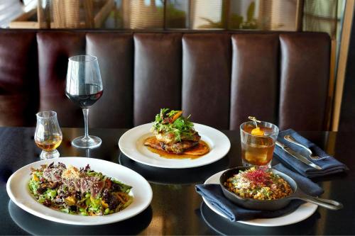 a table with two plates of food and a glass of wine at The Otis Hotel Austin, Autograph Collection in Austin