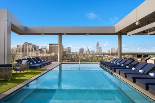 a swimming pool with chairs and a view of the city at The Otis Hotel Austin, Autograph Collection in Austin