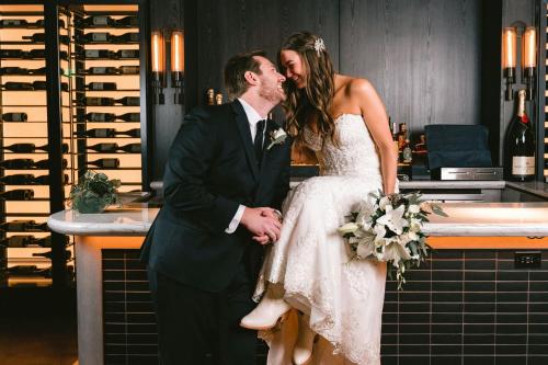 a bride and groom kissing in front of a bar at The Otis Hotel Austin, Autograph Collection in Austin