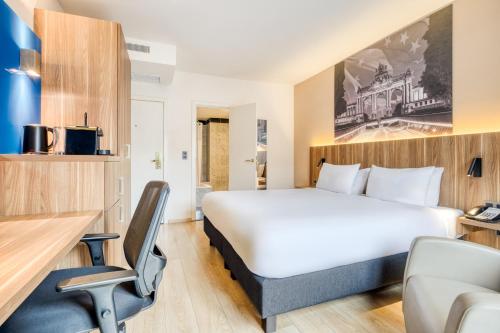 a hotel room with a bed and a desk and a chair at Holiday Inn Brussels Schuman by IHG in Brussels