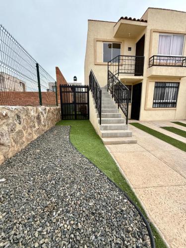 a house with a gate and some grass at La Casita Aeropuerto Guadalajara in San José del Castillo