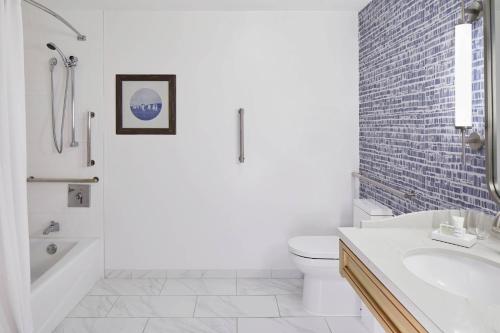 a white bathroom with a tub and a toilet and a sink at Annapolis Waterfront Hotel, Autograph Collection in Annapolis