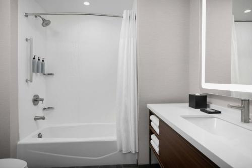 a white bathroom with a tub and a sink at Courtyard by Marriott Bozeman in Bozeman
