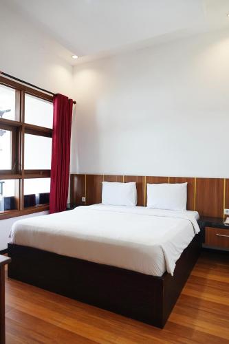 a bedroom with a large bed with a red curtain at Baratha Hotel & Resto in Bondowoso