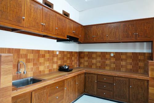 a kitchen with wooden cabinets and a sink at Baratha Hotel & Resto in Bondowoso