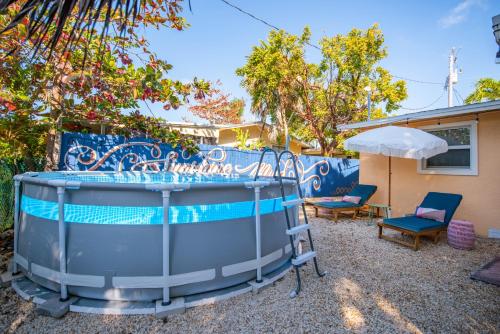 a hot tub in a yard with chairs and an umbrella at Paradise Palms - Movie Theater - Hot Tub - Pool - Arcade - Boat & RV Parking in Marathon