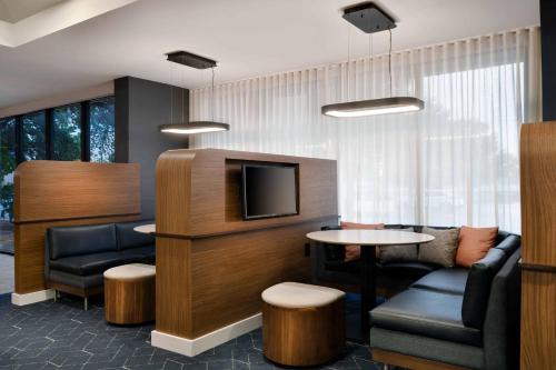 a waiting room with a tv and a table and chairs at Courtyard Austin South in Austin