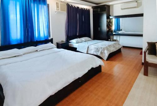 two beds in a hotel room with blue curtains at RedDoorz @ Nena's Hotel Dagupan City in Dagupan