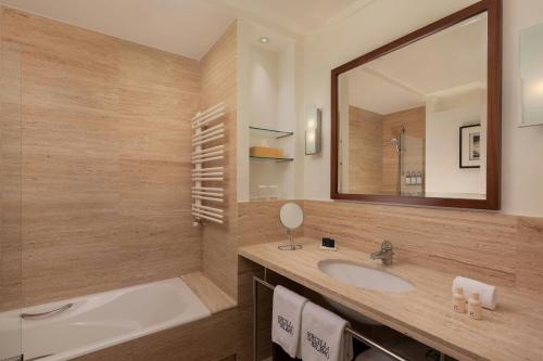 a bathroom with a sink and a tub and a mirror at Hotel Ercilla de Bilbao, Autograph Collection in Bilbao