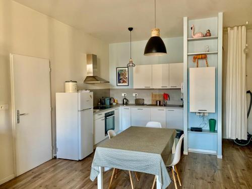 une cuisine avec une table et un réfrigérateur blanc dans l'établissement T3 rénové climatisé avec balcon et Wifi au cœur de Sète - FR-1-338-595, à Sète