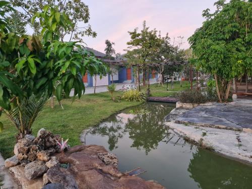 a pond in a garden with a building in the background at Araya Cottage in Ban Bung Thap Tae (1)