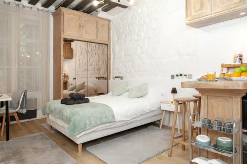 une chambre avec un grand lit blanc dans une pièce dans l'établissement Le Columba-Studio Parisien Saint-Germain, à Paris