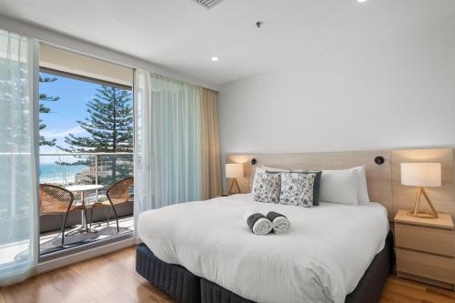 a bedroom with a large bed with two towels on it at Belle Escapes - Lazy Days on Colley Terrace in Glenelg