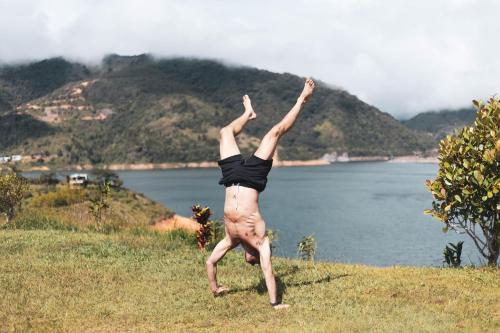 a man doing a handstand in the grass near the water at CABAÑA LAGO CALIMA, frente al lago in Calima