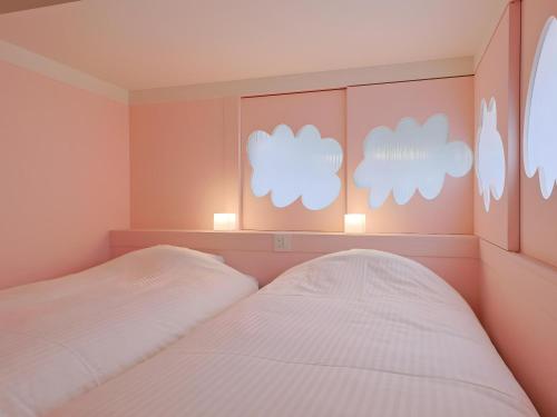 two beds in a room with white clouds on the wall at 日貫一日 マリー in Hinui