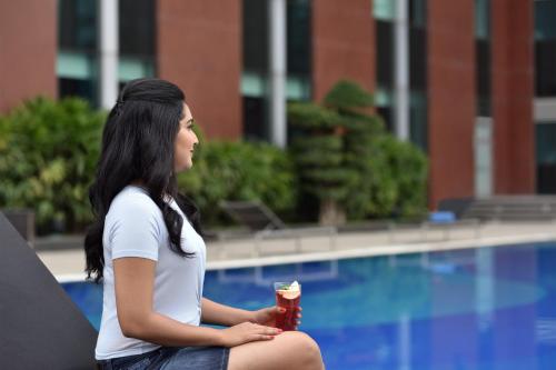 a woman sitting next to a pool with a fire hydrant at Aloft Bengaluru Outer Ring Road in Bengaluru