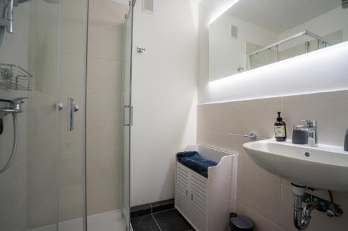 ein weißes Badezimmer mit Waschbecken und Dusche in der Unterkunft Wohnung Krabbenkutter mit sonnigem Südbalkon! in Büsum