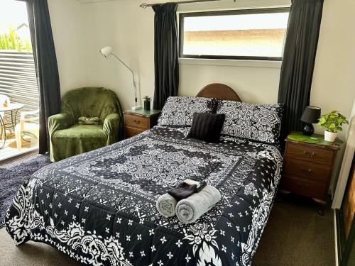 a bedroom with a bed and a chair and a window at B&B on Park in Hokitika
