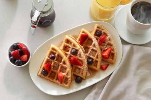 a plate of waffles with strawberries and berries and a cup of coffee at AC Hotel by Marriott Atlanta Airport Gateway in Atlanta