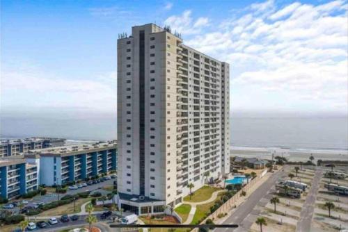 a tall white building with the ocean in the background at Luxe by the Sea - 5-Star Beachfront Escape in Myrtle Beach