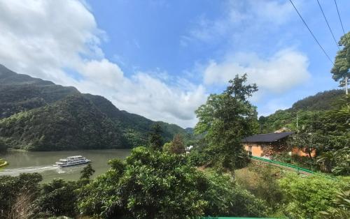 a boat on a river with mountains in the background at Xin'anjiang Landscape Gallery Ran Yuezhu Bed and Breakfast in She